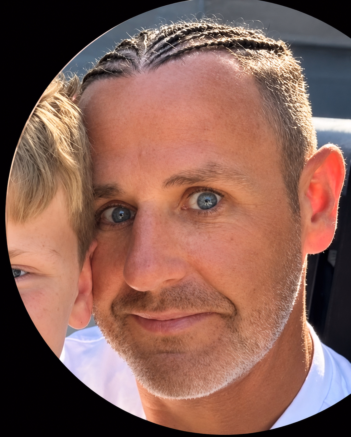 Colin with braided hair, with part of a child visible beside him